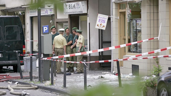 Polizisten untersuchen die Trümmer der Bombenexplosion (Archivbild vom 09.06.2004)