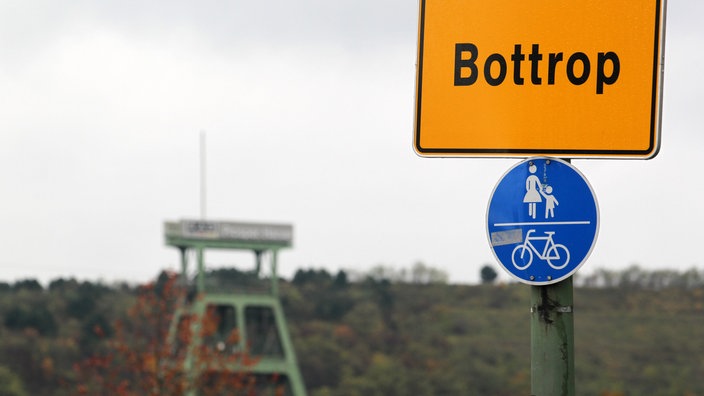 Das Ortseingangsschild für Bottrop steht vor dem Förderturm der Zeche Prosper Haniel