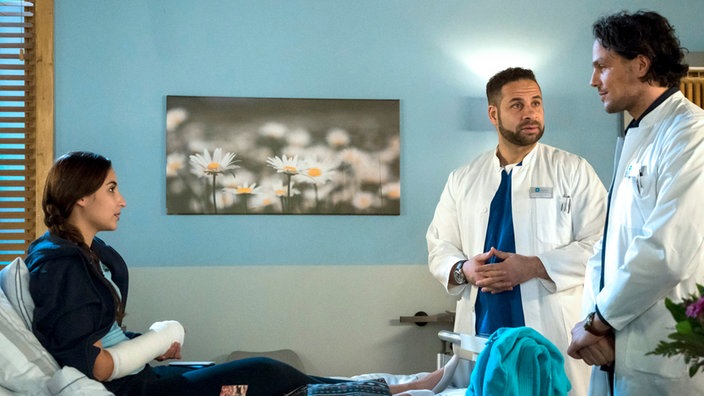 Vor der jungen Patientin Kaja Baldin (Rona Özkan, l.) macht Matteo (Mike Adler, M.) Noah Mattes (Christian Martin Schäfer, r.) klar, wer im Klinikum das Sagen hat.