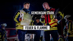 Zwei Feuerwehrleute beraten sich bei Nacht