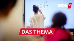 Ein Lehrerin schreibt eine Mathematikaufgabe auf eine digitale Schultafel im Klassenraum einer 4. Klasse einer Grundschule