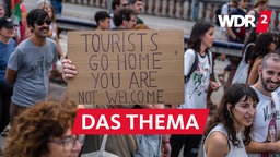 Demonstration gegen Massentourismus in Barcelona: Menschen halten ein Plakat mit der Aufschrift "Tourists go home - you are not welcome"