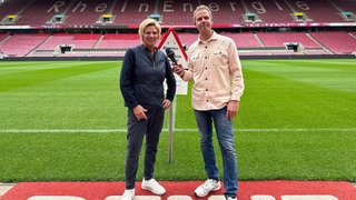 Daniel Schlipf und Claudia Neumann stehen im Rheinenergie-Stadion in Köln. 