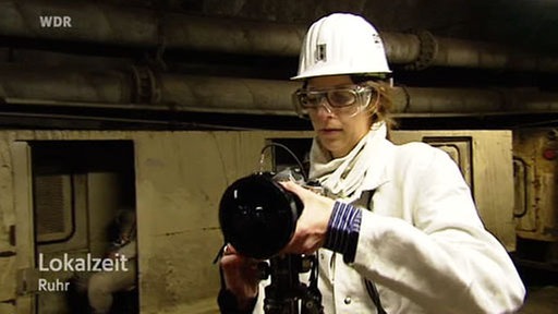 Fotografin mit Schutzkleidung und Spezialkamera im Bergwerk