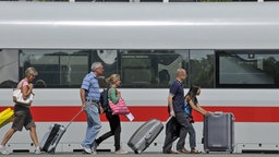 Menschen mit Gepäck vor einem ICE im Bahnhof