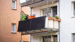 Solarmodule für ein sogenanntes Balkonkraftwerk hängen an einem Balkon.