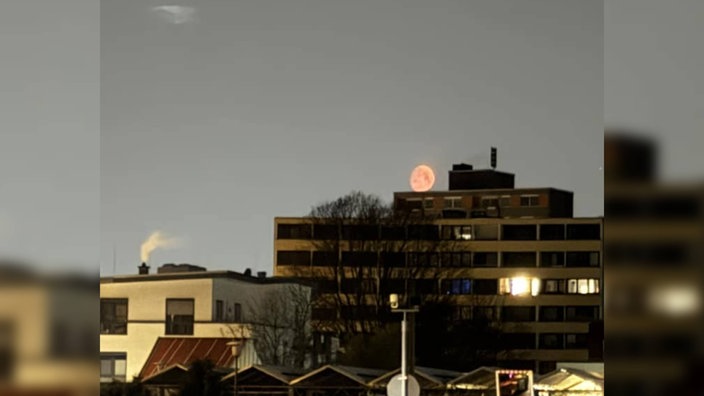 Der Blutmond am Horizont, knapp über einem Gebäude in Deutschland