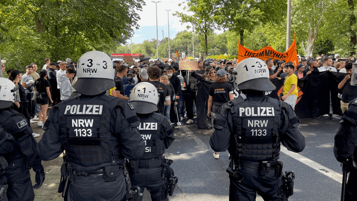 Polizisten mit Schutzhelmen stehen vor dem Demozug in Herford.