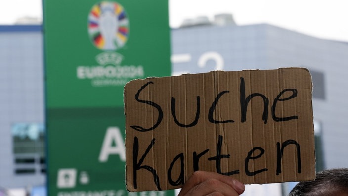 Ein Mann hält ein Schild mit der Aufschrift "Suche Karten" hoch