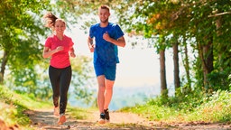 Zwei Personen joggen entspannt durch den Wald