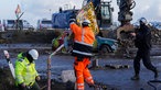 Mit Hilfe eines Polizisten entfernen Arbeiter des deutschen Energiekonzerns RWE das Ortsschild im Dorf Lützerath