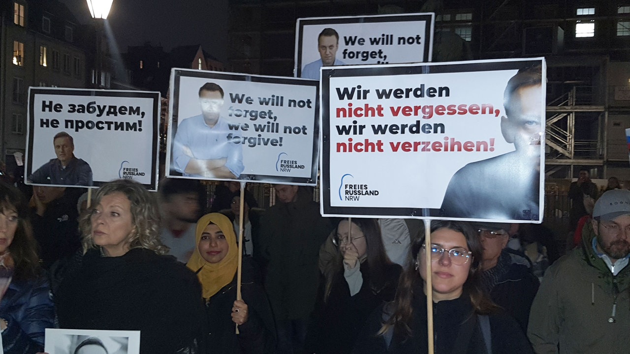 Teilnehmer einer Nawalny Demo in Düsseldorf halten Schilder