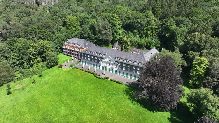 Dreistöckiges Gebäude aus grauem Schiefer und weißer Fassade