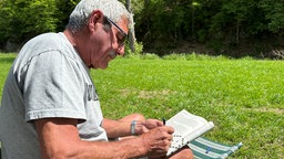 Marcel Allofs spielt Kreuzworträtsel auf der Campingwiese