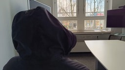 Anonymer UPS Mitarbeiter mit schwarzer Kapuze mit dem Blick auf die Kapuze