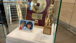 Vitrine mit goldener SChallplatte, einer goldenen Figur und einem Foto von Modern Talking