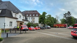 Mehrere Einsatzfahrzeuge stehen vor zwei historischen Gebäuden