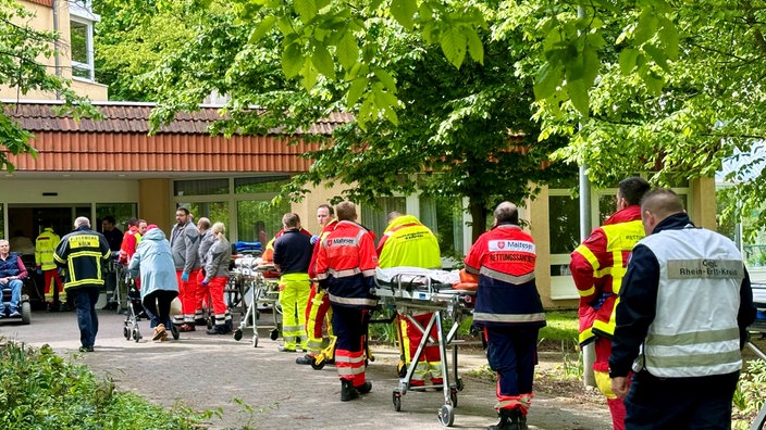 Einsatzkräfte mit Liegen laufen einen Weg entlang