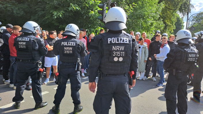 Polizisten stehen Fußballfans gegenüber. 