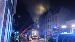 Aus einem Haus dringt eine große Rauchwolke, Feuerwehr löscht