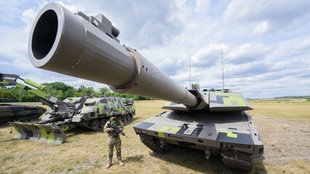 Eine Person steht neben einem Panzer 