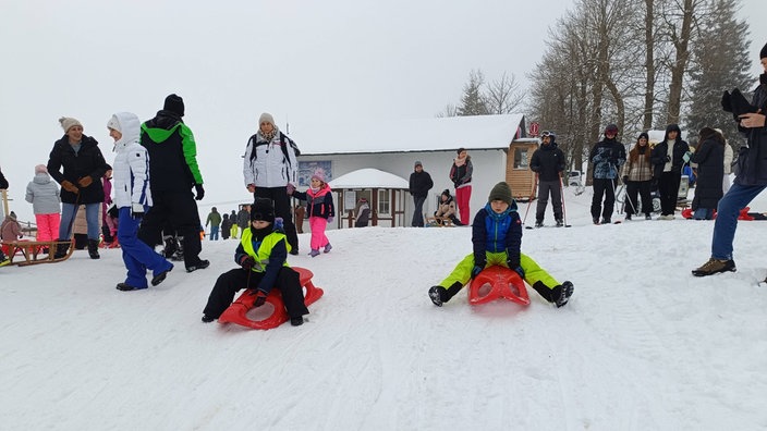 Zwei Kinder rodeln im Postwiesenskigebiet Neuastenberg 