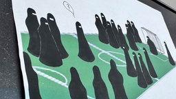 Die Karikatur zeigt voll verschleierte Frauen auf einem Fußballfeld. Niemand weiß, unter welchem Gewand sich der Fußball befindet.