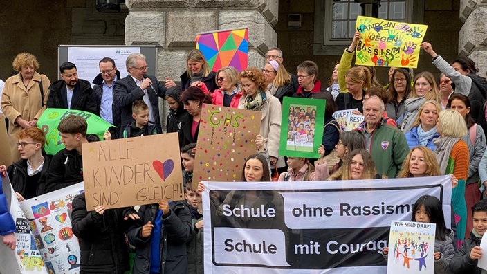 Menschen stshen dicht gedrängt und halten bunte Plakate hoch.