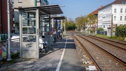 Menschen warten an einem Bahnhof auf den Zug.