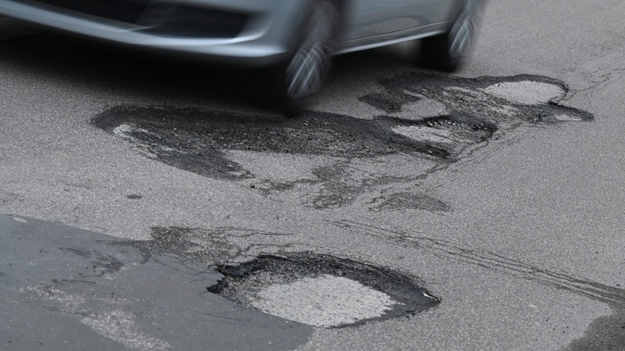 Ein Auto fährt auf ein Schlagloch zu