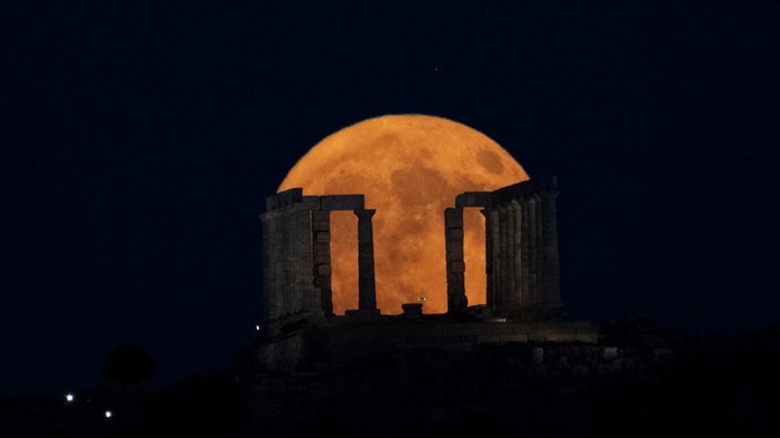 Der Supermond geht hinter dem Poseidon-Tempel am Kap Sounio südlich von Athen auf