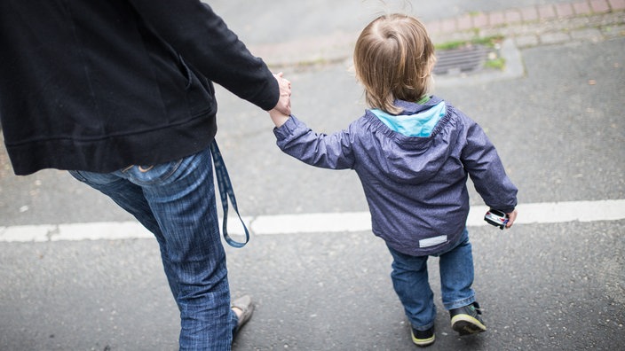 Eine Mutter hält ihren Sohn an der Hand.