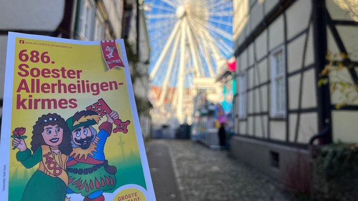 Blick durch Gasse mit Fachwerk auf das Europa-Rad; im Vordergrund ein Flyer 