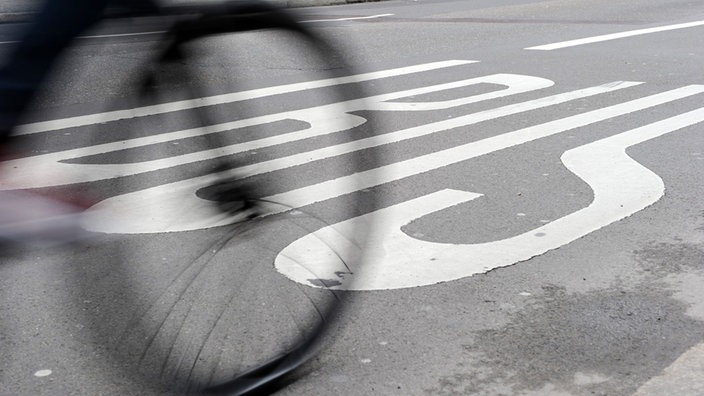 Straße mit Busspur, auf dem schemenhaft ein Fahrrad zu sehen ist