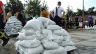 Mehrere Männer stapeln Sandsäcke auf einem Hof