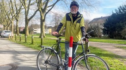 Hans-Ulrich Pohl, Pressesprecher vom ADFC Bielefeld, steht mit einem Fahrrad vor einem Poller. 