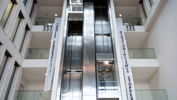 In einem Bürogebäude hängen Stoffbanner von der Balustrade. Auf den meterlangen Bannern steht senkrecht in schwarzen Buchstaben "Tönnies vergesellschaften" und "Neokolonialismus stopppen"