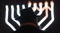 Rabbiner Zalman Gurevitch steht zum Auftakt des Lichterfestes im Dunkeln vor einer Lichtinstallation.