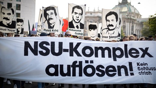 Foto eines Banners auf einer Demonstration zum NSU-Prozess mit der Aufschrift "NSU-Komplex auflösen!" und Schilder von verstorbenen Personen