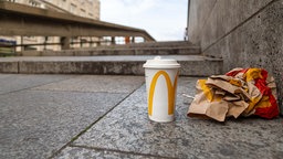 Pappbecher und Fast-Food-Verpackung auf einer Treppe.