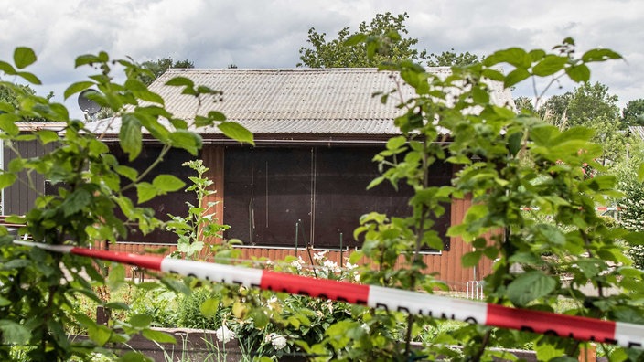 Absperrband umgibt das Grundstück einer Gartenlaube, einer der Tatorte des vermutlichen Haupttäters im Missbrauchsfall von Münster. 