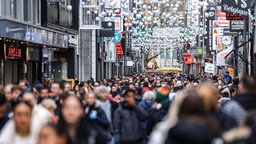 Menschen gehen in Köln durch die Einkaufsmeile Hohe Straße in der Fußgängerzone. 