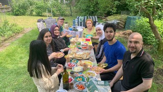 Eine Gruppe von Menschen beim Picknick im Schrebergarten