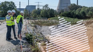 Menschen mit Bauhelmen stehen am Rande der Südostlink-Trasse