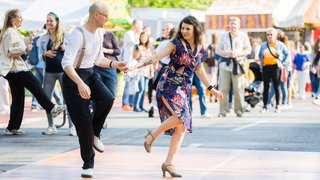 Ein Mann und eine Frau tanzen beim Karneval der Kulturen in Berlin 2023 miteinander Swing