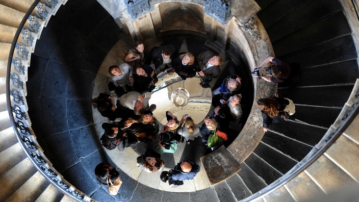 Wendeltreppe; Menschen schauen vom Fuß der Treppe nach oben