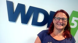 Portrait der Kabarettistin Anny Hartmann vorm WDR 5 Logo im Sendestudio