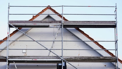 Ein Gerüst steht vor einem Neubau. Symbolbild