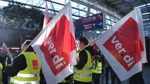 Mitglieder der Gewerkschaft Verdi stehen mit Fahnen bei einem Streik in einem Teminal des Düsseldorfer Flughafens. 