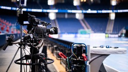 Eine Fernsehkamera ist auf das Spielfeld einer Sporarena gerichtet. 